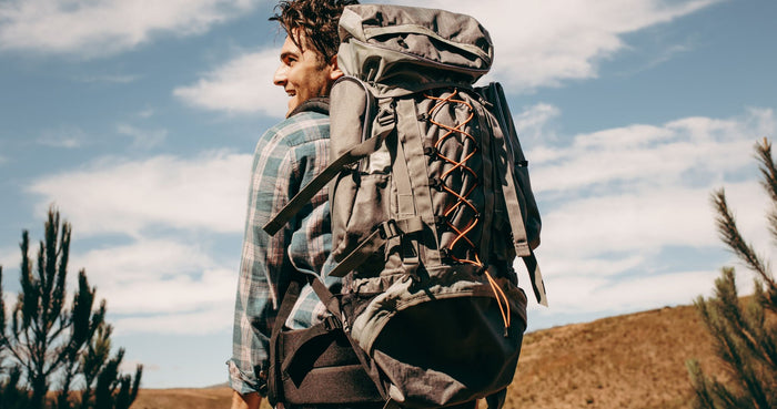 Mann mit Wanderrucksack auf dem Rücken in der Natur: wanderrucksack richtig einstellen
